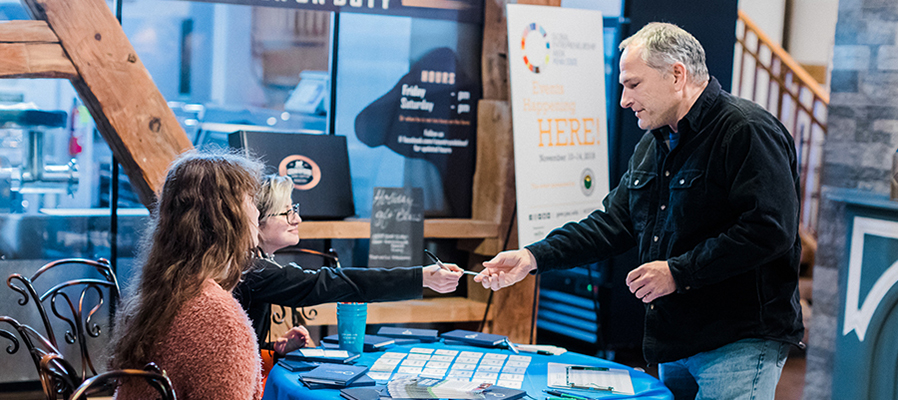 Person being handed a name badge at a registration table during Global Entrepreneurship Week, which connects entrepreneurs and small businesses