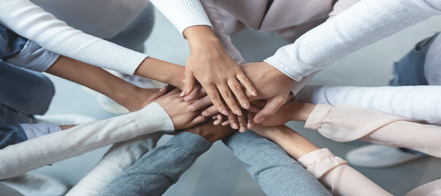 Diverse group of people participating in a hand huddle.